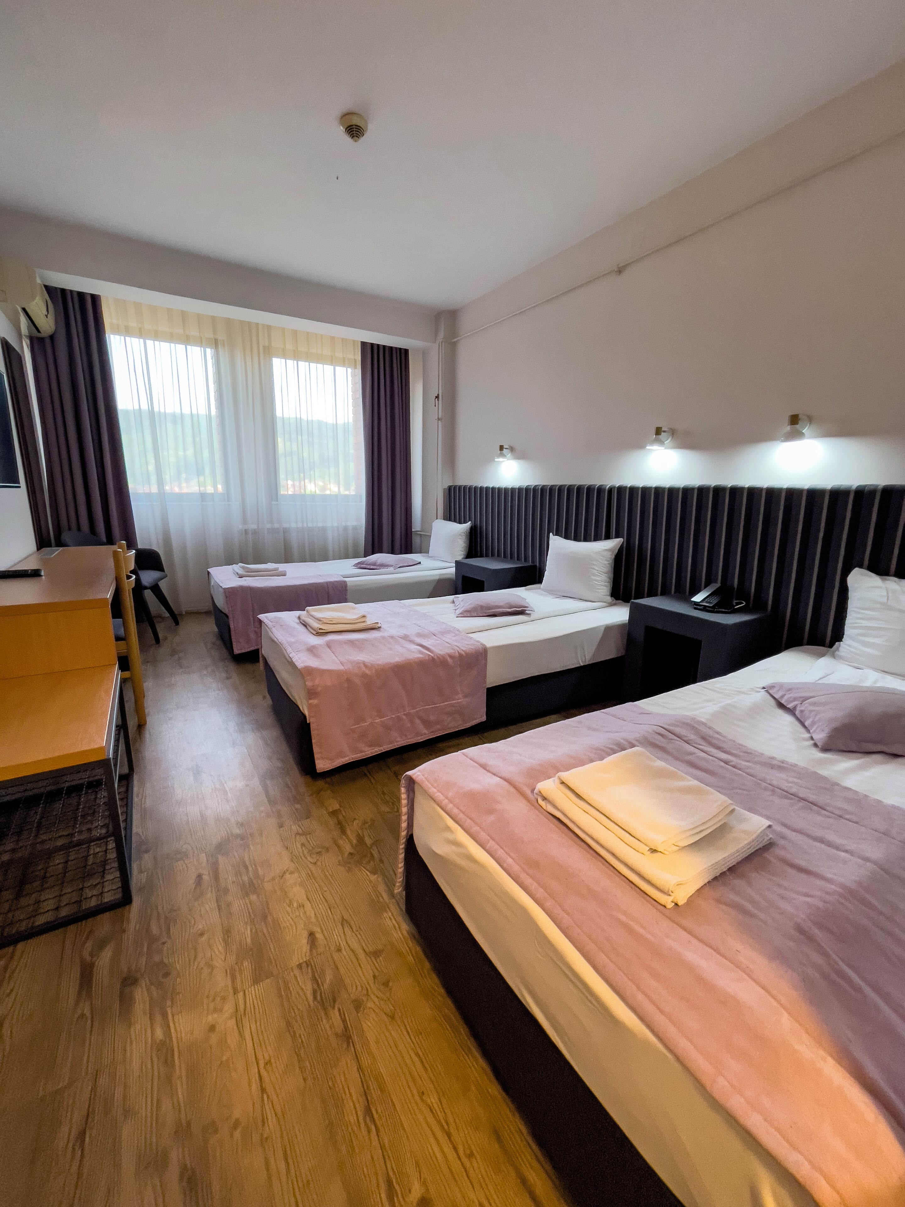 A hotel room with two single beds, a desk, and a chair.