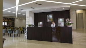 A reception area with a dark reception desk, a receptionist, and a sign indicating 'Reception' and 'Information Desk'. - Zepter Hotel Drina Bajina Bašta, member of Zepter Hotels (Bajina Bašta)