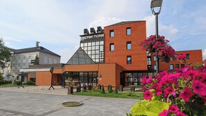 A modern hotel with a prominent 'zeppers hotel' sign, a brick facade, and a landscaped courtyard with flower beds. - Zepter Hotel Drina Bajina Bašta, member of Zepter Hotels (Bajina Bašta)