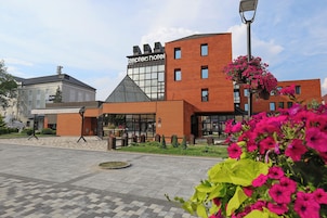 Un hotel moderno con un llamativo letrero 'zeppers hotel', fachada de ladrillo y un patio ajardinado con macizos de flores.