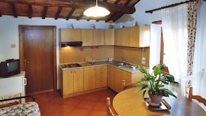 Una cocina compacta con armarios de madera, un lavamanos y un comedor con mesa y sillas.