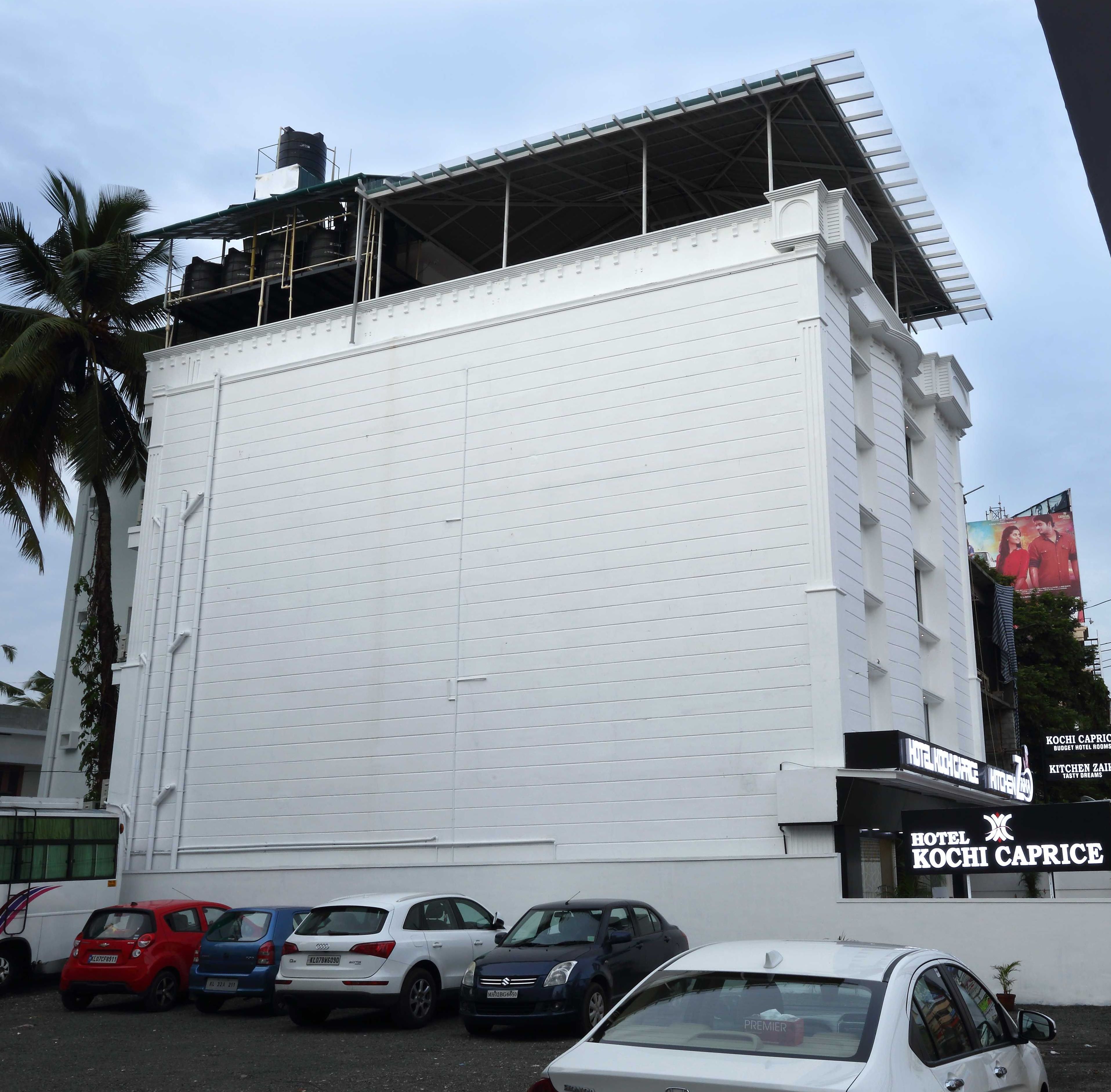 Un edificio con fachada blanca y un cartel que indica Hotel Kochi Caprice.