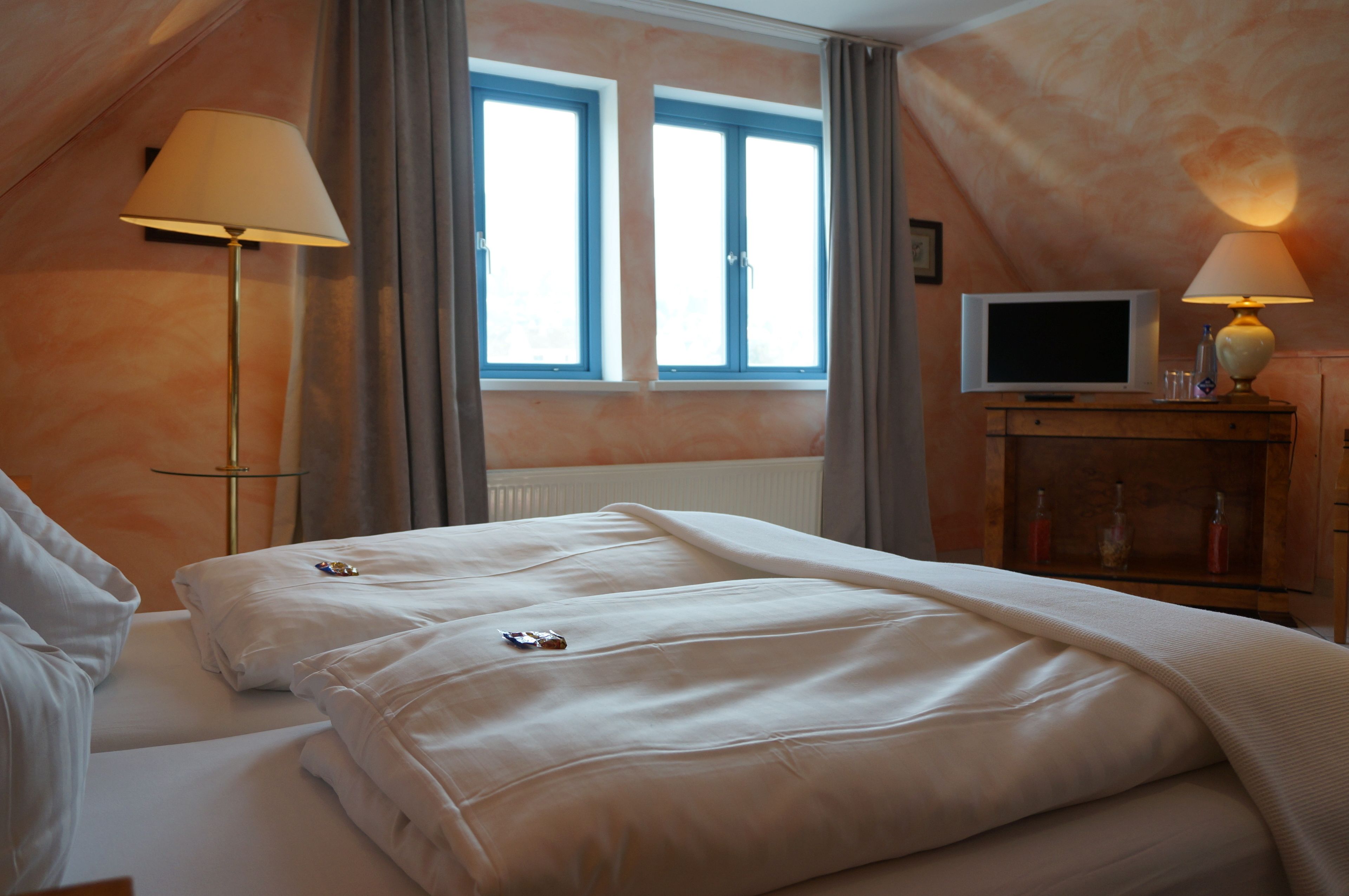 A hotel room with two beds, a TV, and a lamp.