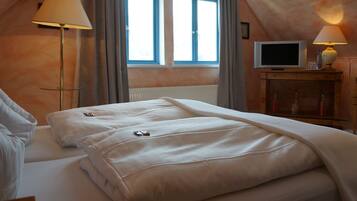 A hotel room with two beds, a TV, and a lamp.