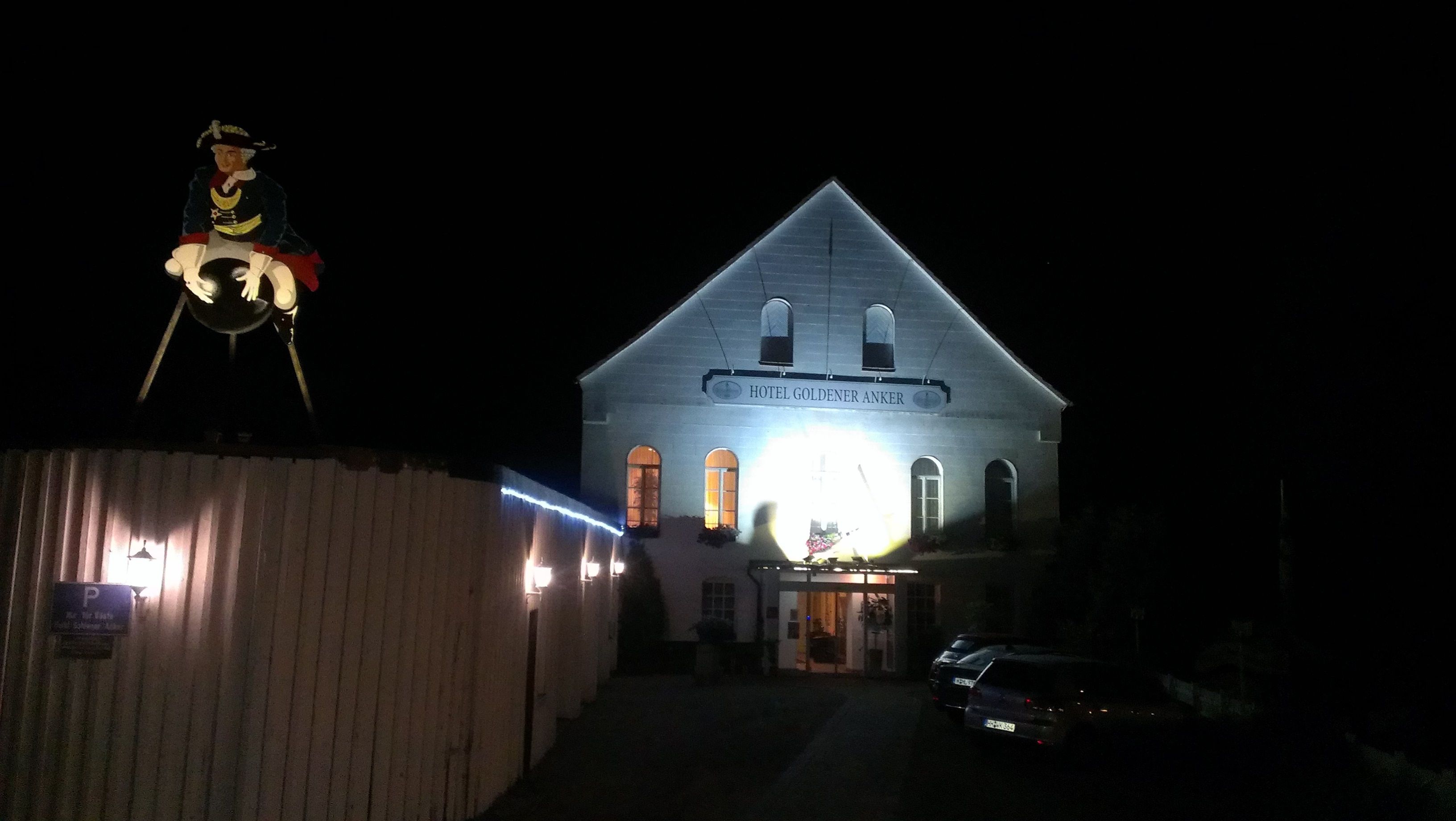 A building with a sign reading "HOTEL GOLDENER ANKER" at night.