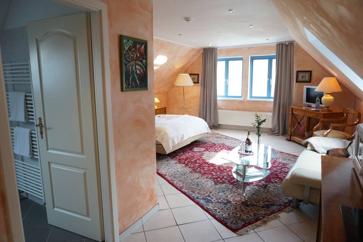 A bedroom with a bed, a desk, a chair, a lamp, and a window.
