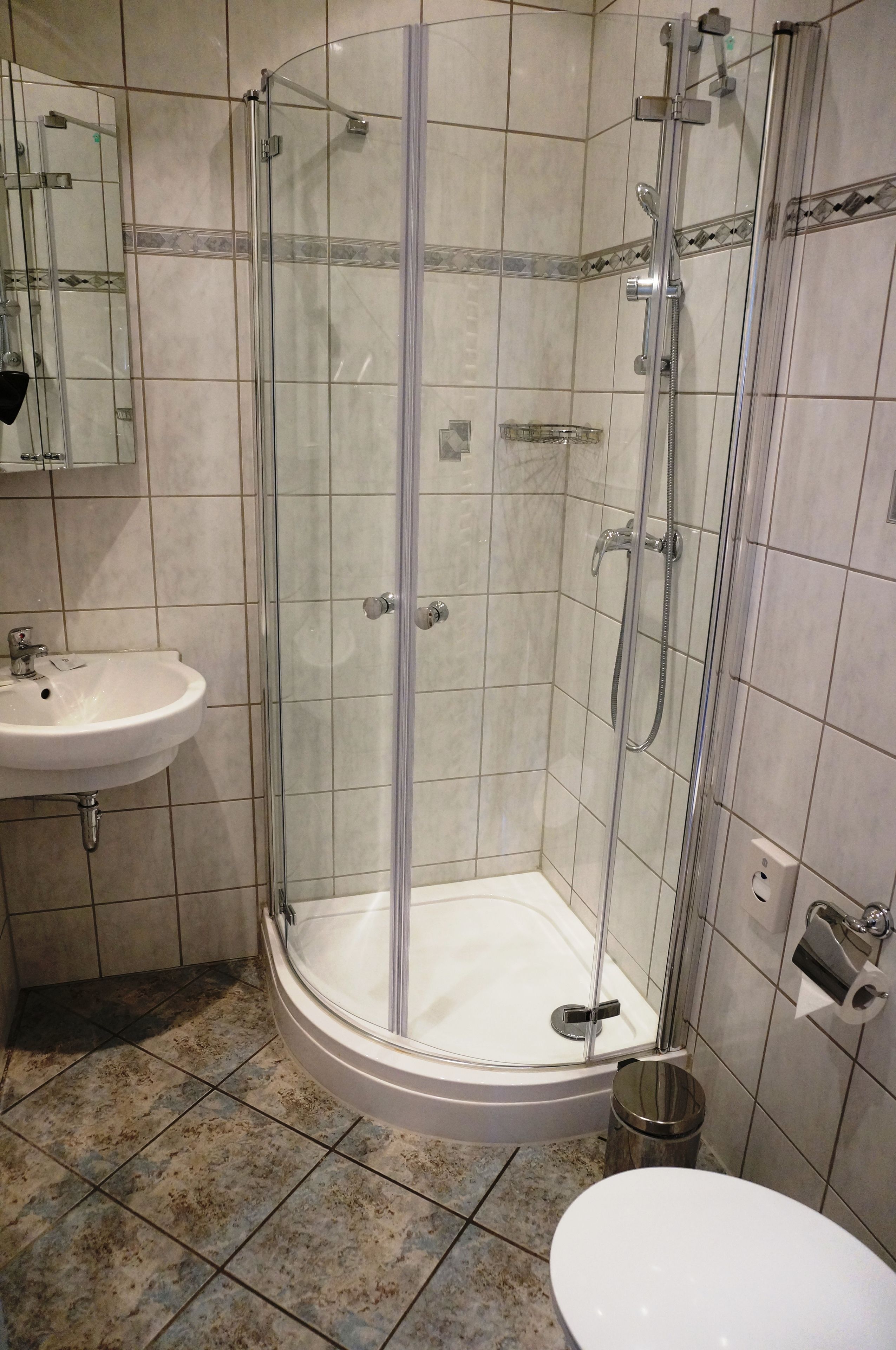 A bathroom with a glass-enclosed shower, a sink, and a toilet.
