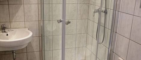 A bathroom with a glass-enclosed shower, a sink, and a toilet.