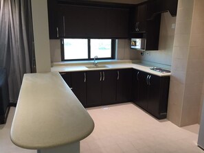 Une cuisine de taille réduite, avec des meubles de couleur sombre, un plan de travail et une fenêtre.
