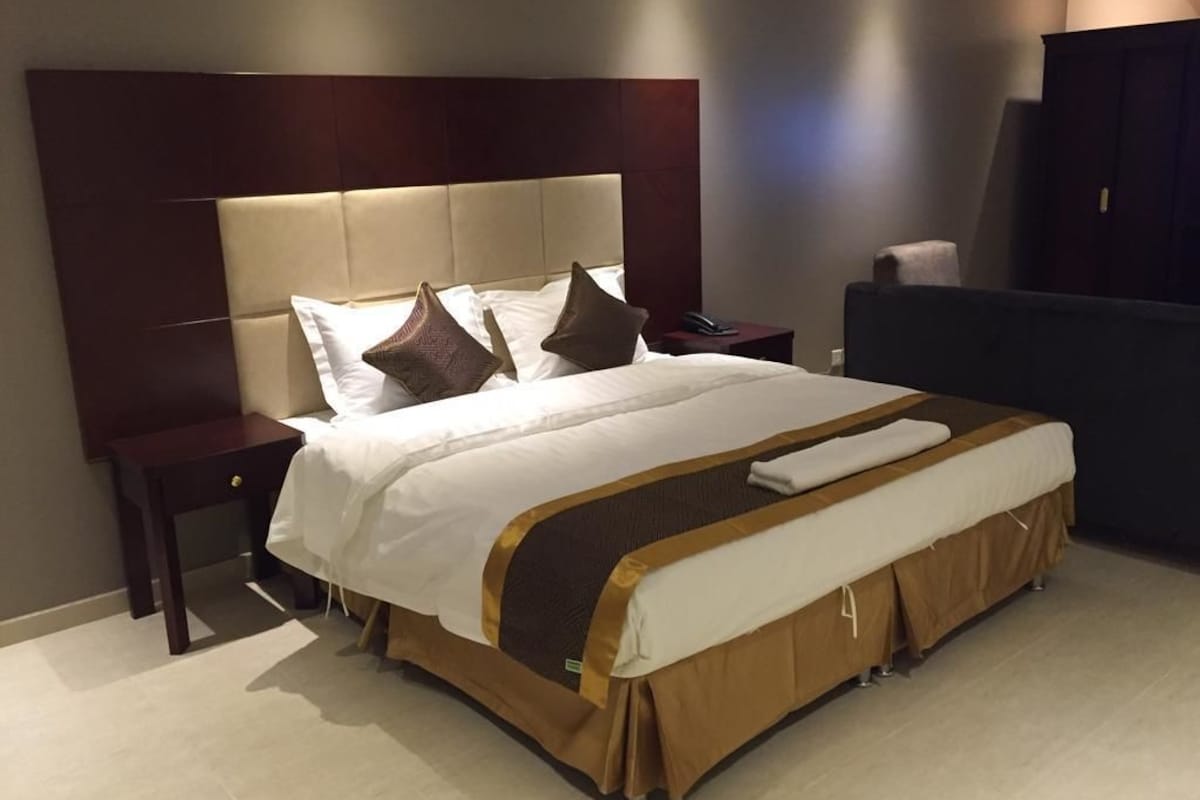 Une chambre d’hôtel avec un grand lit, une table de chevet, un bureau et une armoire.
