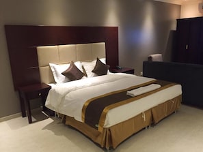 Une chambre d’hôtel avec un grand lit, une table de chevet, un bureau et une armoire.