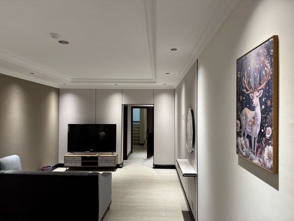 Un salon moderne avec un téléviseur à écran plat, un canapé et un grand tableau représentant un cerf.