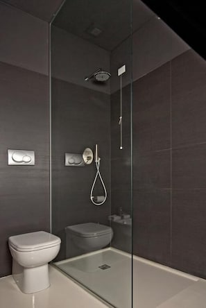 A modern bathroom with a glass-enclosed shower, a toilet, and a bidet. - House5 (Trieste)