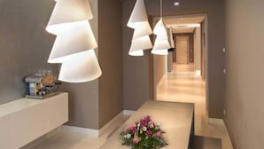 A modern hallway with pendant lighting, a reception desk, and a floral arrangement. - House5 (Trieste)