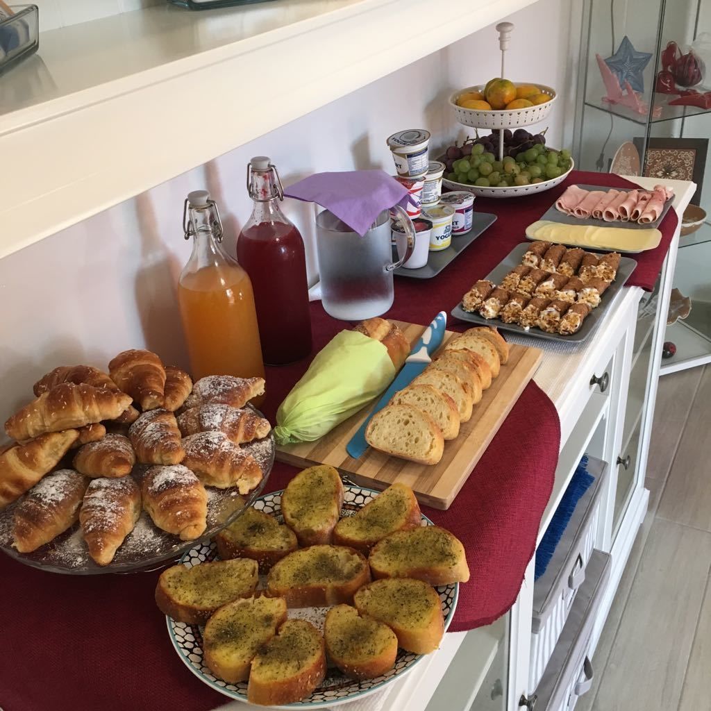 A buffet table with various food items including pastries, bread, and fruits.