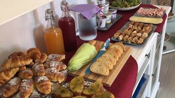 A buffet table with various food items including pastries, bread, and fruits.