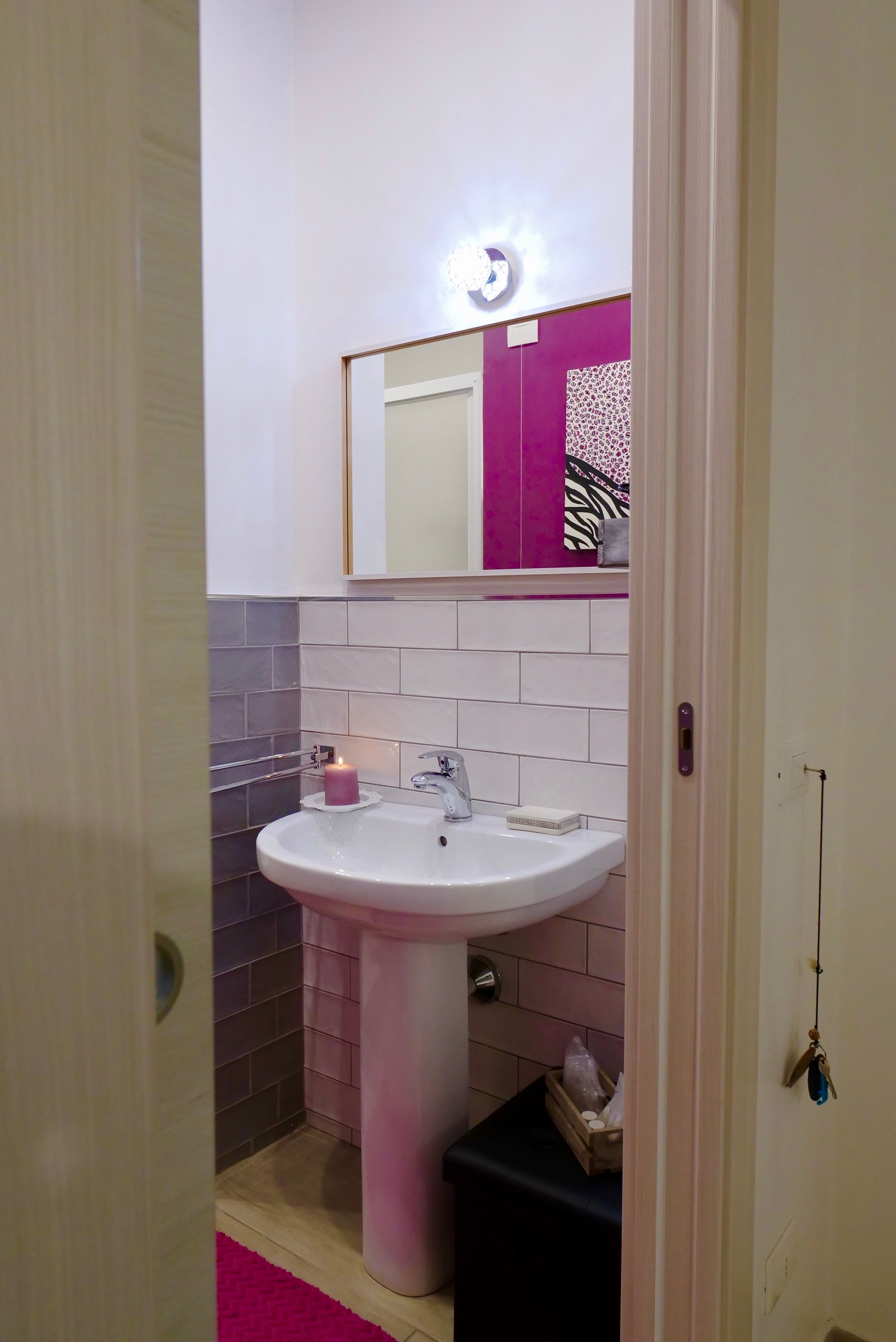 A bathroom with a white sink, a mirror above it, and a pink decorative item on the sink.