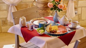 En frukostuppsättning med en tekanna, en kopp, en tallrik med mat och en vas med blommor på ett bord.