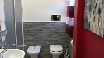 A bathroom with a bidet, toilet, and sink.