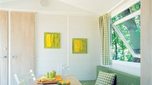 Una habitación con una mesa de madera, sillas, un sofá verde y dos obras de arte amarillas en la pared.