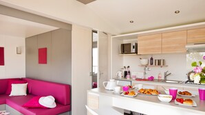 Una cocina moderna con barra, un sofá rosa y alimentos para el desayuno sobre la encimera.