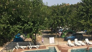 Una piscina con toboganes, rodeada de sillas de descanso y una zona vallada.