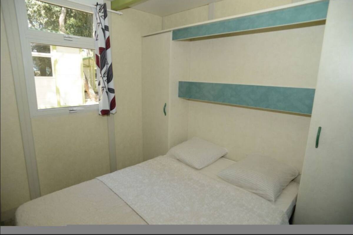 Een slaapkamer met een bed, een raam en een gordijn.