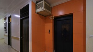 A hallway with orange walls, two doors, and a sign that reads "DO NOT USE IN CASE OF FIRE." - OYO 10562 Paharganj (New Delhi)