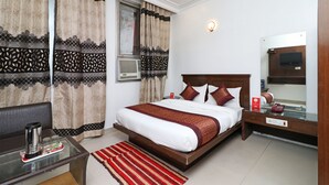 A hotel room with a bed, bedside table, and a mirror. - OYO 10562 Paharganj (New Delhi)