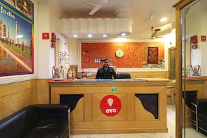 Una reception con una sveglia, un cartello per 'Kumari Tours' e un segnale che indica 'Vietato fumare'.