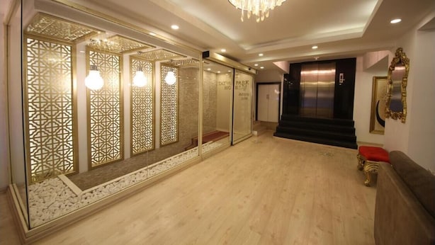 Vestíbulo de hotel con candelabro, un mostrador de recepción y una escalera que conduce a los ascensores.