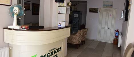 A reception desk with a clock, framed pictures, and a sign for Burhaniye Merkez Hotel.