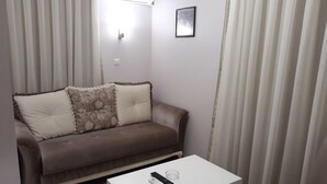 Un saló amb un sofà marró, una taula de centre blanca i un comandament a distància a sobre.