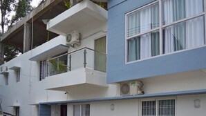 Un immeuble à plusieurs étages doté de balcons, de climatiseurs et de plantes en pot.