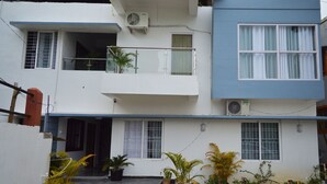 Un immeuble résidentiel de deux étages doté d’un balcon, de climatiseurs et de plantes en pot.