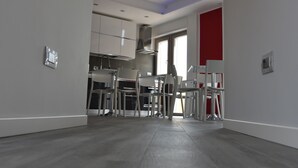A spacious, modern kitchen with white cabinetry and a dining area with chairs. - La Lira (Fiumicino)