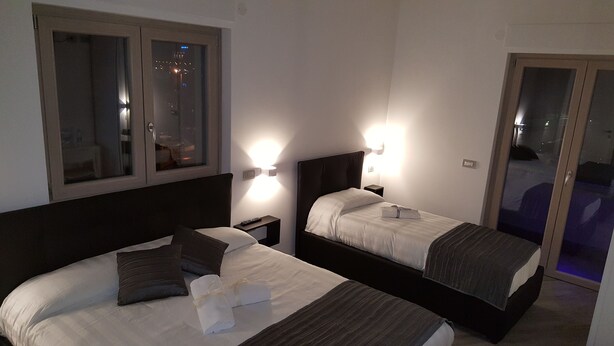 A hotel room with two beds, a window, and a door leading to a balcony. - La Lira (Fiumicino)