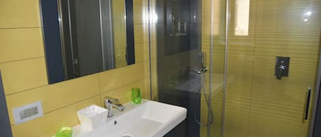 Een badkamer met een wit wastafelmeubel, een spiegel en een douche met glazen wanden.