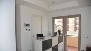 A modern, minimalist room with a white desk, a laptop, and a small potted plant. - La Lira (Fiumicino)