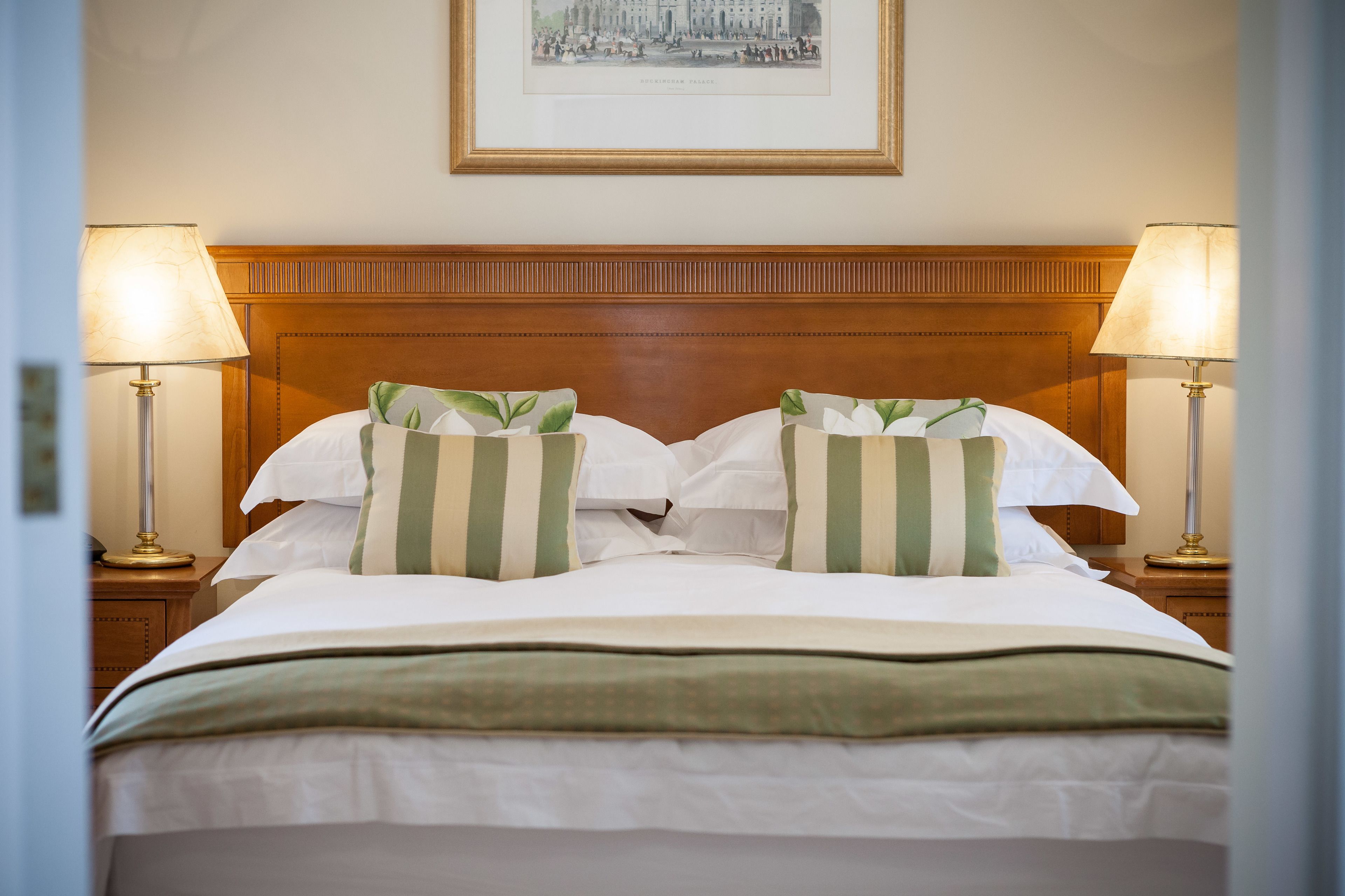 A neatly made bed with striped pillows, a wooden headboard, and two bedside lamps.