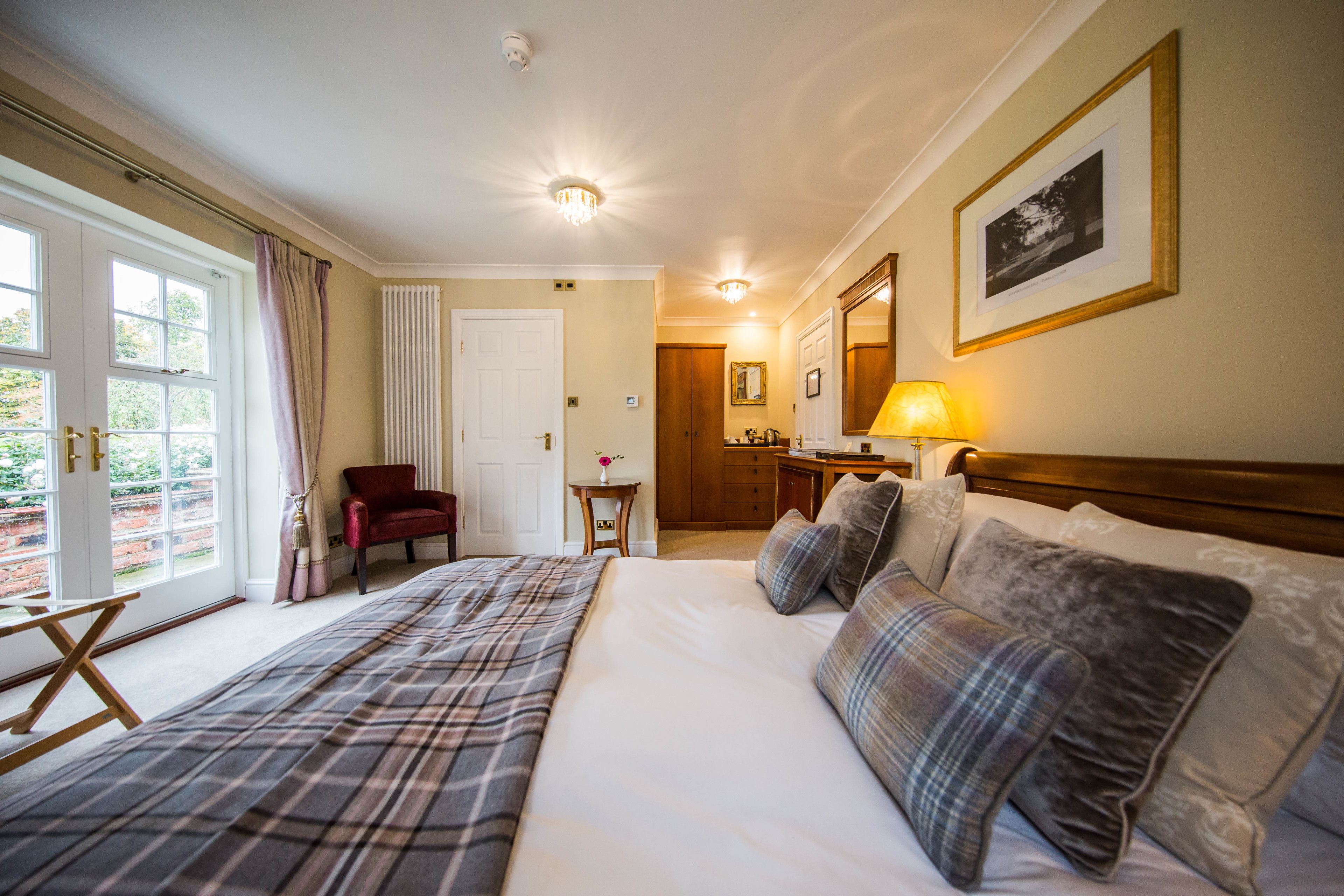Hotelkamer met een groot bed, een bureau met lamp, een stoel en uitzicht op het buitengebied door een raam.