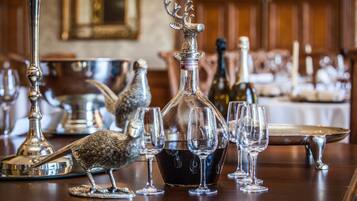 A dining table with silverware, wine glasses, and a decorative silver bird.