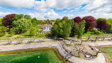 A park with a pond, benches, and a house in the background.