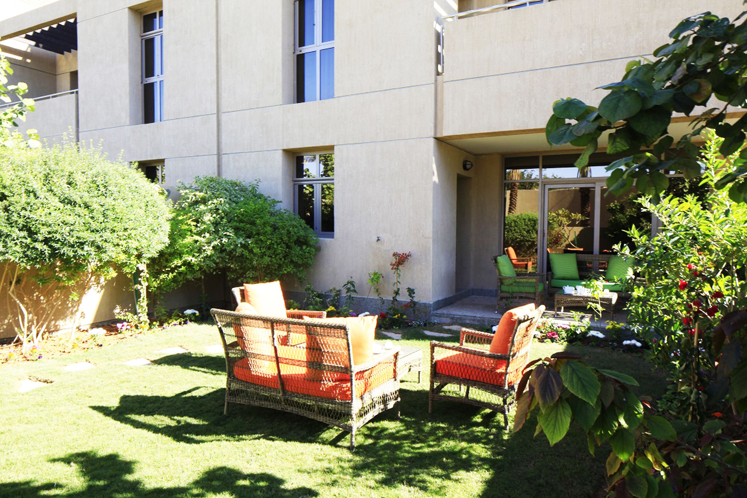 A modern building with a flat facade, large windows, and a covered outdoor seating area with wicker furniture.