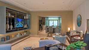 Un salón moderno con televisor, asientos cómodos, una estantería y un amplio ventanal.