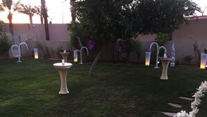 Un espace extérieur aménagé en jardin, avec une pelouse, des fontaines décoratives et un arbre.