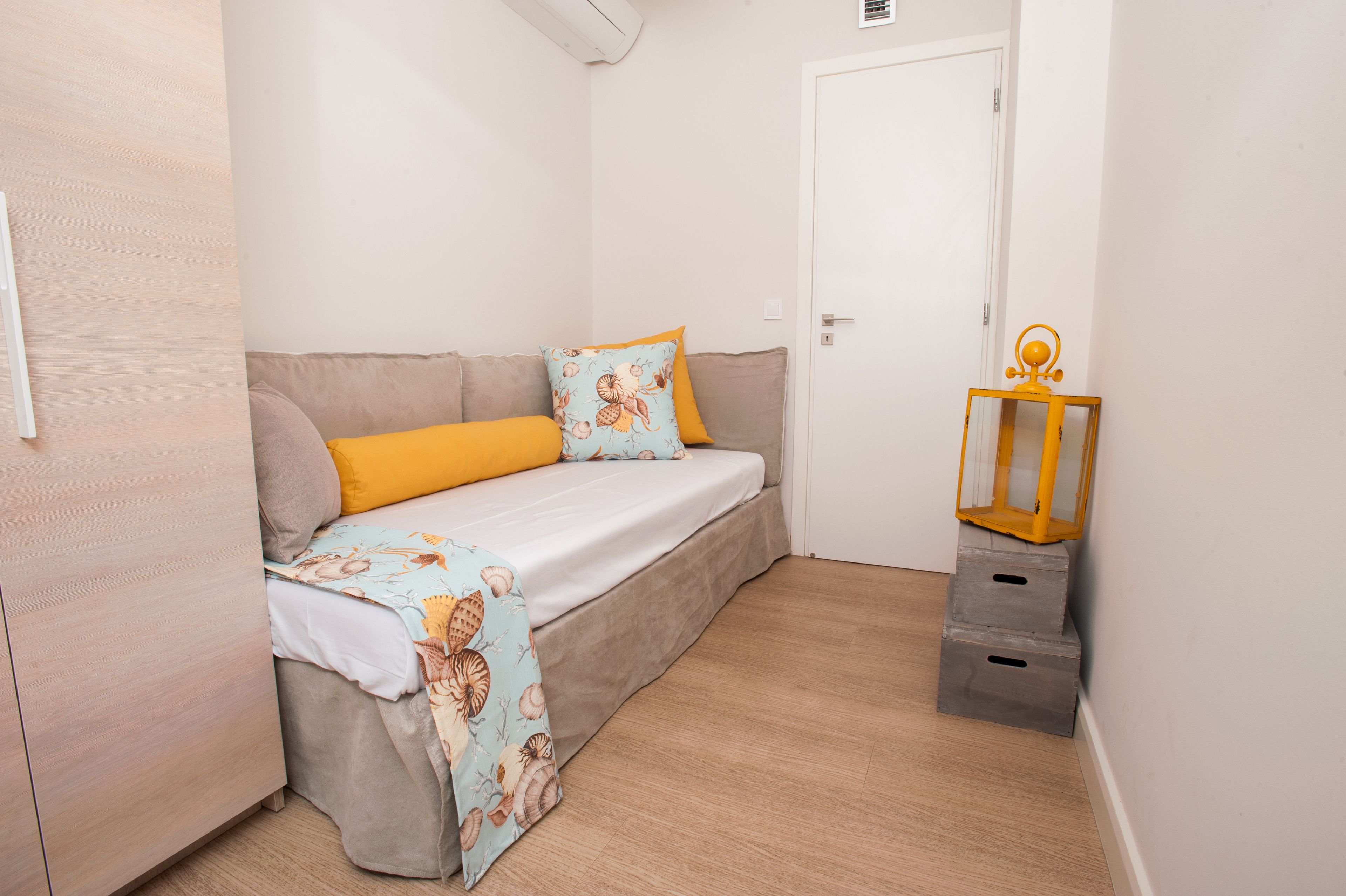 A small, cozy room with a single bed, a wooden wardrobe, and a small table with a lantern.