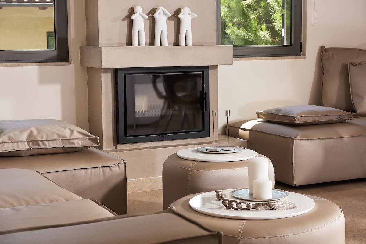 Una sala moderna con chimenea, sofás de cuero, otomanas y un televisor.