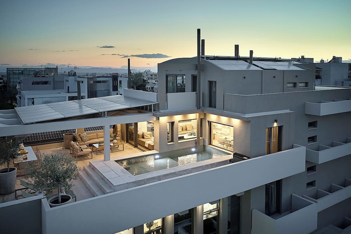 Un moderno edificio de varios pisos con piscina en la azotea y zona de estar al aire libre.