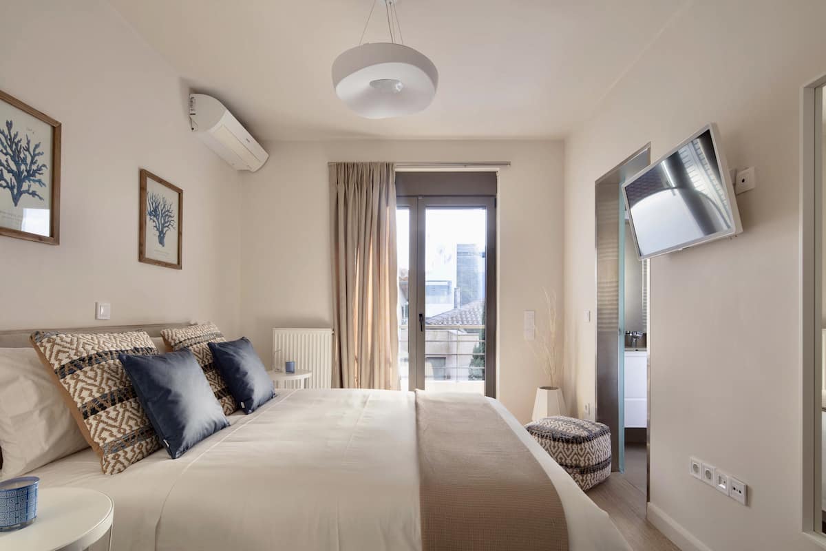 Una habitación de hotel moderna con una cama grande, un televisor de pantalla plana y vistas a la ciudad desde la ventana.